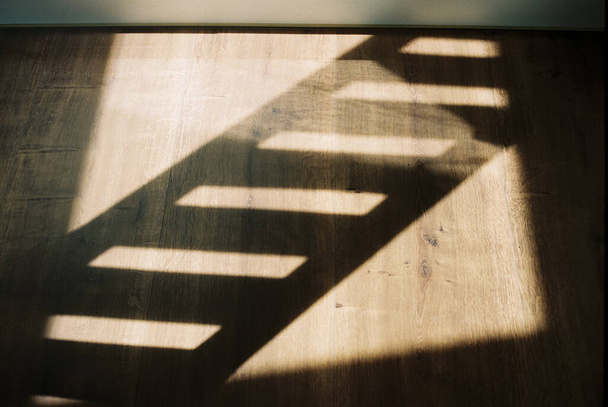 Фотография теней лестниц, отражающихся на деревянных полах - Фото, изображение