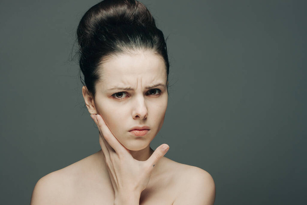 Frau mit nackten Schultern sammelte unzufriedene Haare Hand auf Gesicht - Foto, Bild