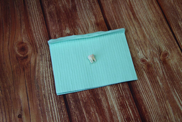 Diente de sabiduría extraída en una servilleta en el fondo de madera, vista superior - Foto, Imagen