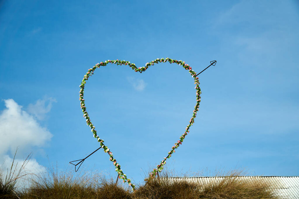 Large love and arrow decoration on top of the hills over the sky - Photo, Image