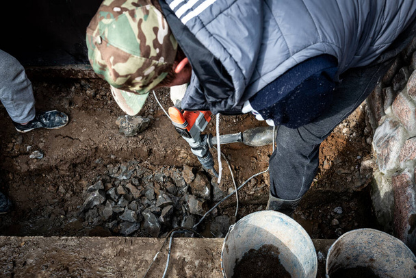 Mannelijke werknemer reparatie oprit oppervlak met drilboor, graven en boren betonweg. - Foto, afbeelding