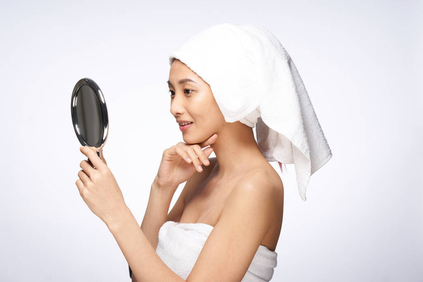 jolie femme avec une serviette sur sa tête miroir dans les mains touche visage cosmétologie - Photo, image