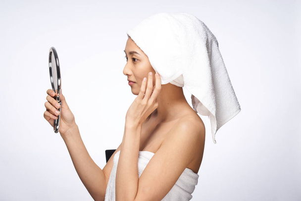 красива жінка з рушником на голові дзеркало в руках торкається косметології обличчя
 - Фото, зображення