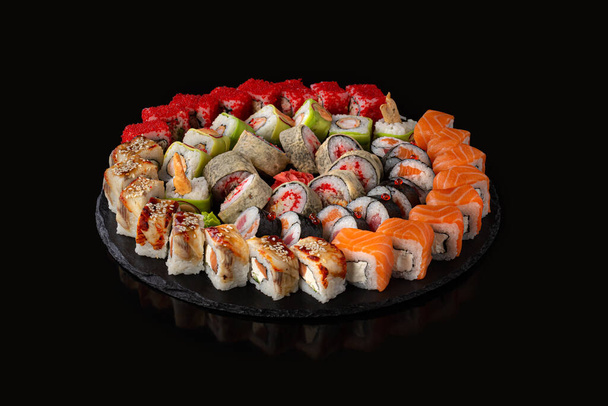 Set de sushi. Rollos con caviar rojo anguila salmón y verduras sobre fondo negro - Foto, Imagen