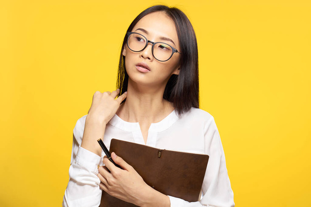 elegant woman with notepad in hands official office yellow isolated background - 写真・画像