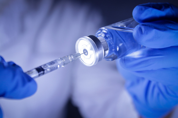 Lekarze lub naukowcy trzymają strzykawki i fiolki ze szczepionką COVID-19 w celu wykonania wstrzyknięć w celu leczenia pacjentów w szpitalach. Eksperymenty medyczne zapobiegają rozprzestrzenianiu się koronawirusu - Zdjęcie, obraz