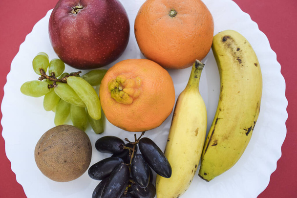 Mix of many fruits like Apple, Oranges, malta, two types of bananas, chiku, green grapes and black grapes and sapota Very healthy breakfast.Indian Asian fruits served during fasting days like ekadashi - Photo, Image