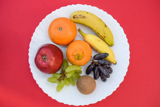 Mezcla de muchas frutas como manzana, naranjas, malta, dos tipos de plátanos, chiku, uvas verdes y uvas negras y sapota Desayuno muy saludable.Frutas asiáticas indias servidas durante los días de ayuno como ekadashi - Foto, Imagen