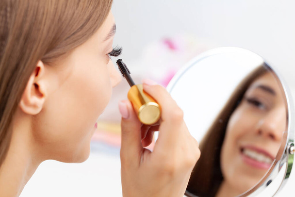 Femme assise près du miroir et appliquant le maquillage - Photo, image