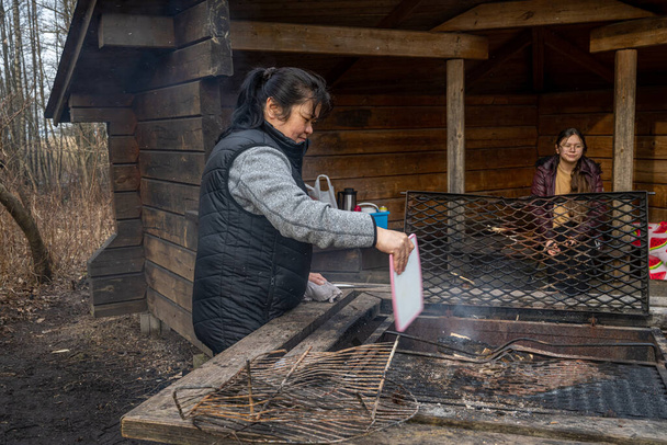Orta yaşlı Asyalı bir kadın kamp yerinde Souvlakia pişiriyor.. - Fotoğraf, Görsel