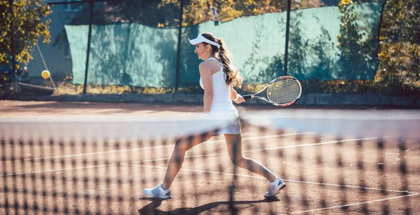 Žena dostane míč na tenisovém kurtu - Fotografie, Obrázek