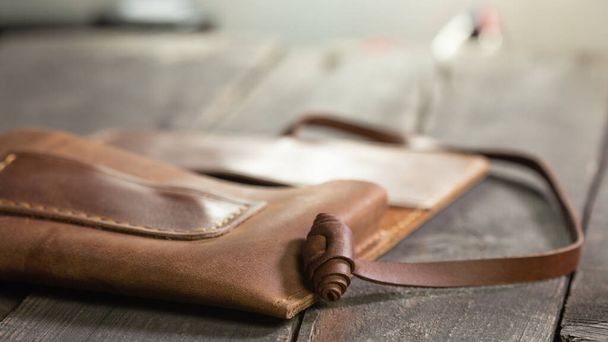 Brown fashion tobacco pouch leather on wood background. Craft product handmade. - Photo, Image