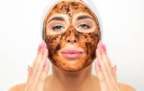 Frote facial de la piel. Máscara de café molido en la cara de una hermosa mujer joven. Cosmetología natural orgánica. - Foto, imagen