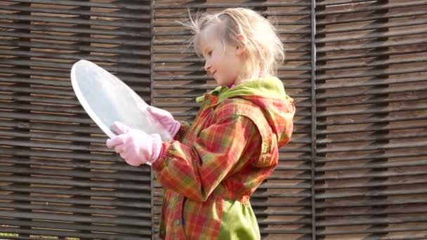 Dziewczyna trzyma owalną kopertę lodową w dłoniach i patrzy na odbicia. - Materiał filmowy, wideo