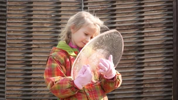 Het meisje houdt een ovale ijsvlo in haar handen en onderzoekt hem van alle kanten.. - Video