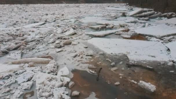巨大な氷の負荷ラトビアのオグレ川でドリフト。雪の日に空中ドロンショット。春の川での混雑。移動する氷塊の大きな塊 - 映像、動画