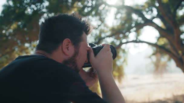 Takaisin näkymä ammattivalokuvaaja ottaa kuvia luonnonpuistossa auringonlaskun aikaan - Materiaali, video