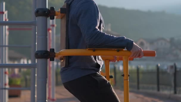 Fitness homme faire de l'exercice sur les bars sur les appareils de gymnastique de rue - Séquence, vidéo