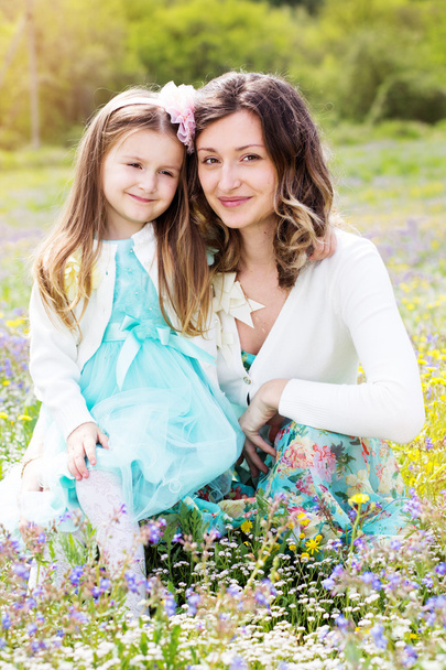 Mother and daughter in field with colorful flowers - Foto, Bild