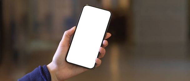 Close-up vista da mão feminina segurando smartphone com tela de mock up mostrando à câmera em fundo embaçado, caminho de recorte - Foto, Imagem