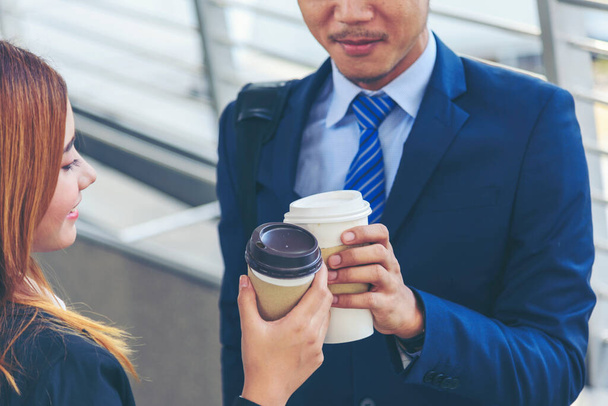 Biznesmen Bizneswoman pije kawę w mieście poza biurem nowoczesnego miasta. Trzymanie za ręce zabiera filiżankę kawy rozmawiając razem szczęśliwa zabawa. Partner Biznes ludzie formalny garnitur z filiżanką kawy - Zdjęcie, obraz