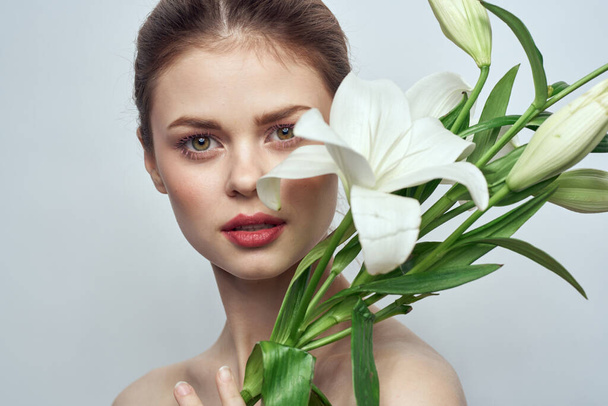 mujer con flores blancas sobre fondo gris modo de maquillaje de primer plano retrato - Foto, imagen