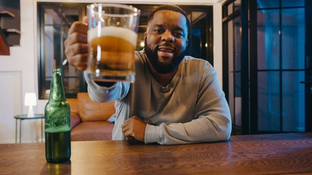 Středního věku Afroameričan pije pivo baví šťastný moment večer párty akce on-line oslavy prostřednictvím videohovoru doma. Sociální distancování, karanténa pro koronavirus. Úhel pohledu nebo POV - Fotografie, Obrázek