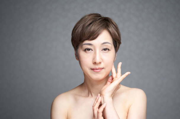 Mulher japonesa de meia-idade verificando a firmeza da pele - Foto, Imagem