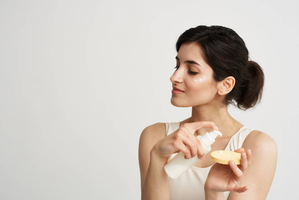 mujer en camiseta blanca Esponja con crema cosméticos de salud de la piel limpia - Foto, imagen