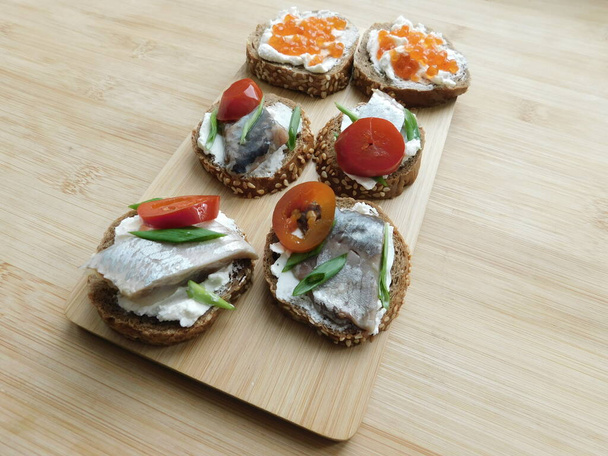 Sanduíches com caviar vermelho e peixe vermelho em pranchas de madeira fundo preto - Foto, Imagem