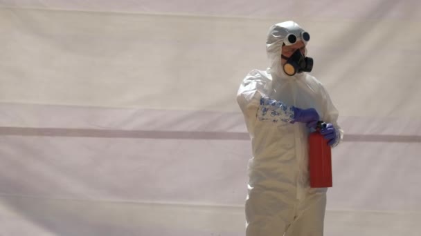 Mann in weißem Chemikalienschutzanzug benutzt Feuerlöscher, Zeitlupe. - Filmmaterial, Video