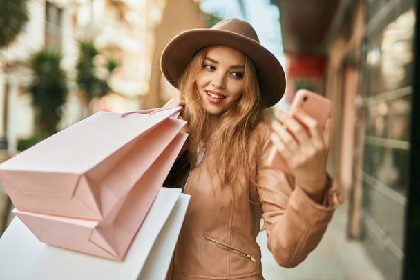 Mladá blondýna dívka nakupování pomocí smartphone ve městě. - Fotografie, Obrázek