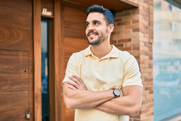 Молодой латиноамериканец улыбается счастливо стоя над дверью нового дома. - Фото, изображение