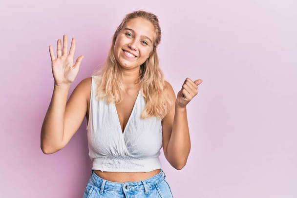 Young blonde girl wearing casual clothes showing and pointing up with fingers number six while smiling confident and happy.  - Photo, image