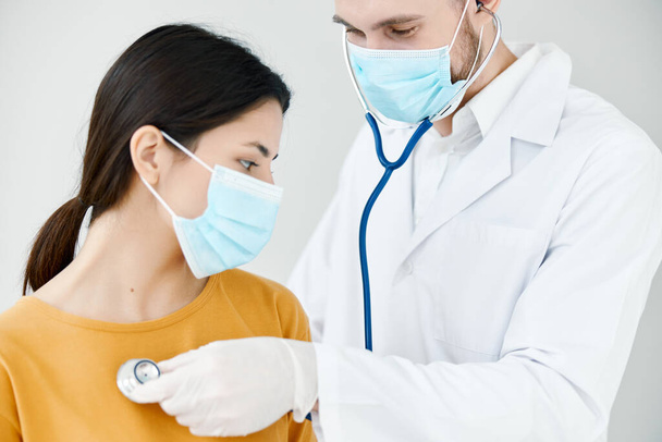 médico profesional en un vestido médico examina a una paciente con una máscara azul vacunación covid - Foto, imagen