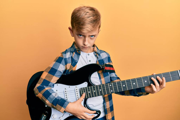 Kis kaukázusi srác elektromos gitáron játszik szkeptikus és ideges, rosszalló feldúlt a probléma miatt. negatív személy.  - Fotó, kép