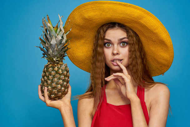 Nainen keltaisessa hatussa ananaksella käsissä tunteet hauskaa elämäntapaa kesä hedelmä sininen tausta - Valokuva, kuva