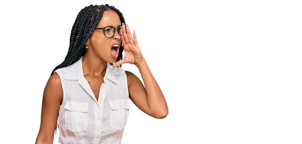 Beautiful hispanic woman wearing casual clothes and glasses shouting and screaming loud to side with hand on mouth. communication concept.  - Foto, Bild