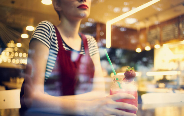 mulher na moda em vestido vermelho descansando em um café com uma bebida na mão - Foto, Imagem