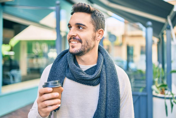 Young hispanic man smiling happy drinking take away coffee at the city. - Foto, Imagen