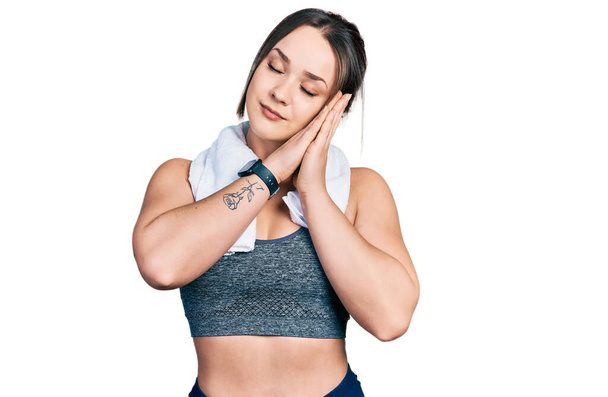 Young hispanic girl wearing sportswear and towel sleeping tired dreaming and posing with hands together while smiling with closed eyes.  - Foto, Bild