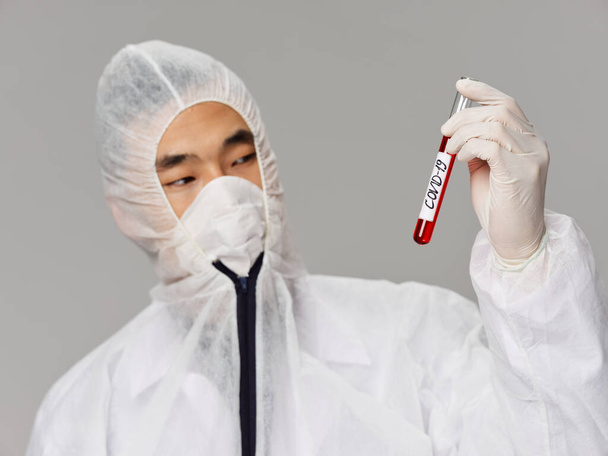 Азиатский мужчина держит ковид-19 исследования крови серый фон - Фото, изображение