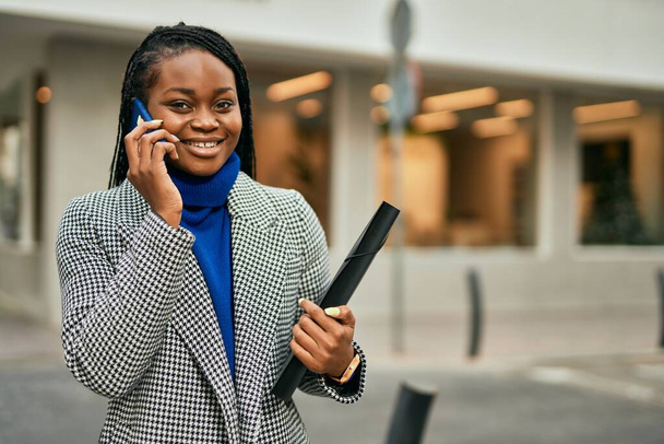 若いアフリカ系アメリカ人の実業家が市内のスマートフォンで幸せな会話をしています. - 写真・画像