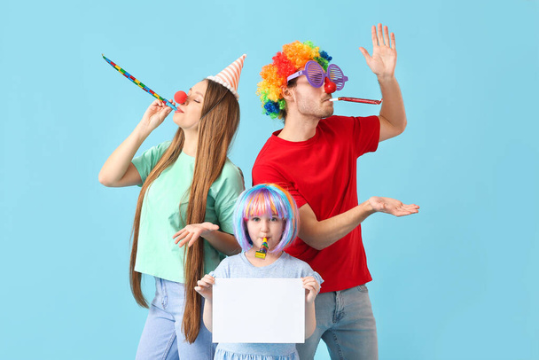 Família jovem em disfarce engraçado e com folha de papel vazia no fundo de cor. Abril Dia dos Tolos celebração - Foto, Imagem