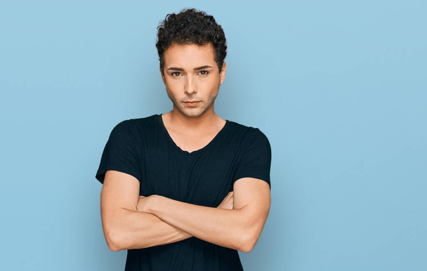 Young handsome man wearing casual black t shirt skeptic and nervous, disapproving expression on face with crossed arms. negative person.  - Photo, Image