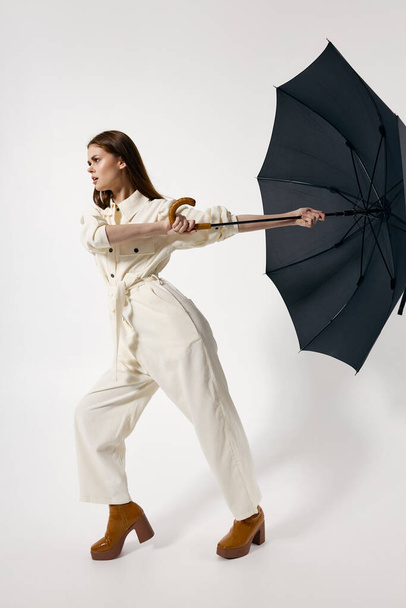 vrouw in wit pak met een paraplu uit de wind moderne stijl - Foto, afbeelding