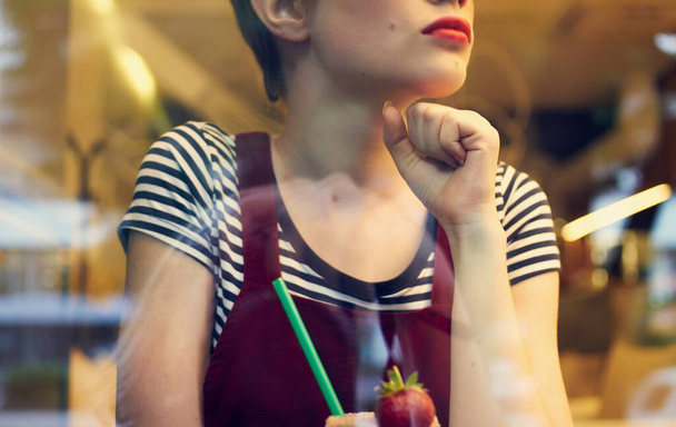 фешенебельная женщина в красном сарае отдыхает в кафе с напитком в руке - Фото, изображение