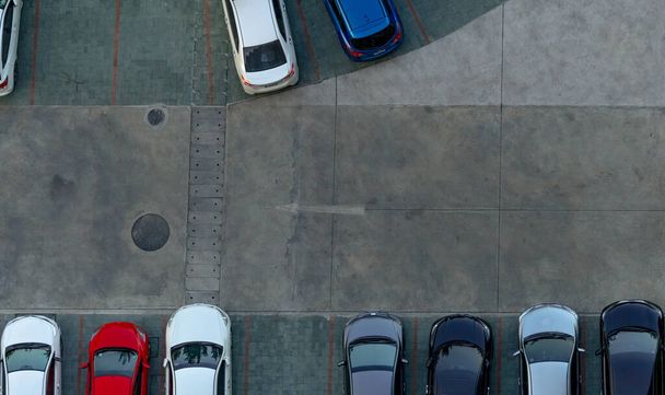 Top view concrete car parking lot. Aerial view of car parked at car parking area of apartment. Outdoor parking space with empty slot. One way traffic sign on road. Above view outside car parking lot. - Photo, Image