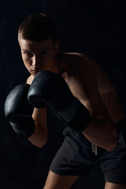 man in bokshandschoenen op zwarte achtergrond workout bodybuilder fitness - Foto, afbeelding