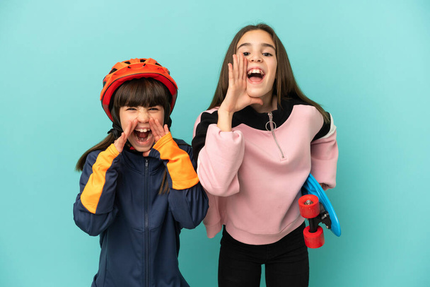 Pikkusiskot harjoittelevat pyöräilyä ja luistelija eristetty sinisellä taustalla huutaa ja ilmoittaa jotain - Valokuva, kuva